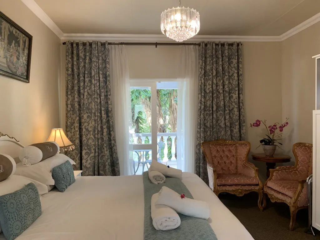 Cozy bedroom with large bed floral curtains and armchairs near a window