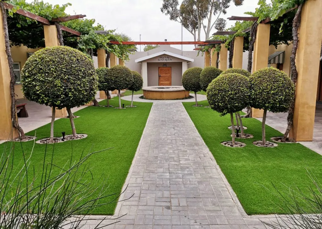 Pathway with topiary trees leading to a small building with a wooden door