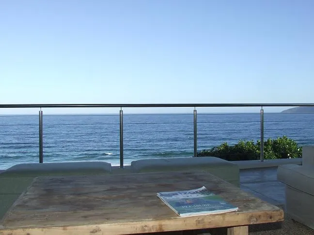 Wooden table with magazine overlooking ocean from a balcony with railing