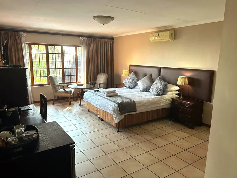 Bedroom with a large bed two chairs and a window with curtains