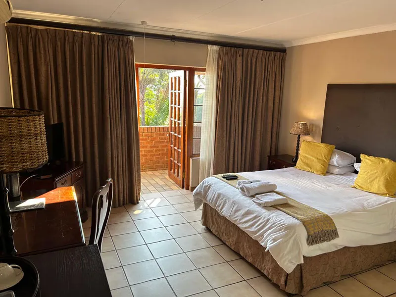 Hotel room with a bed desk and open balcony door with curtains