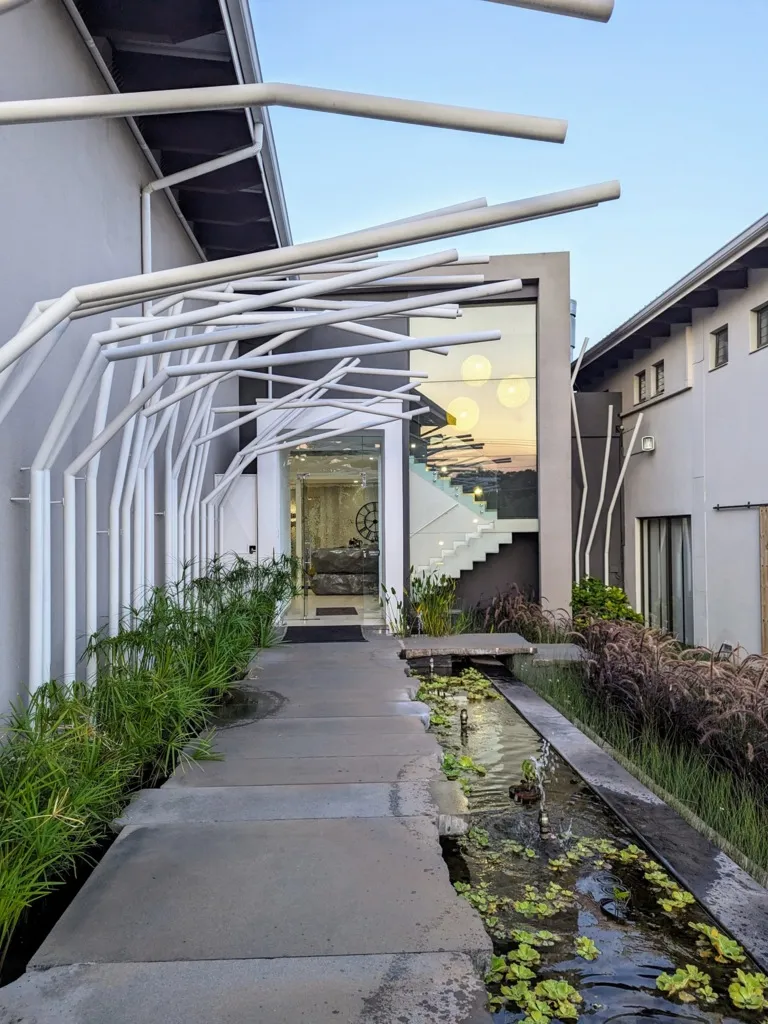 Modern building entrance with a water feature and plants along the pathway
