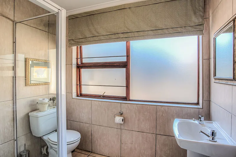 Small bathroom with toilet sink frosted window and shower area