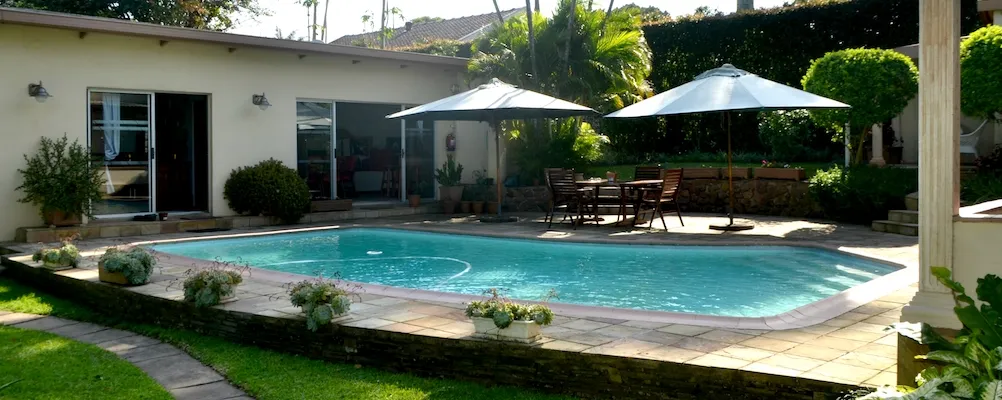 Swimming pool in a backyard with patio furniture and potted plants