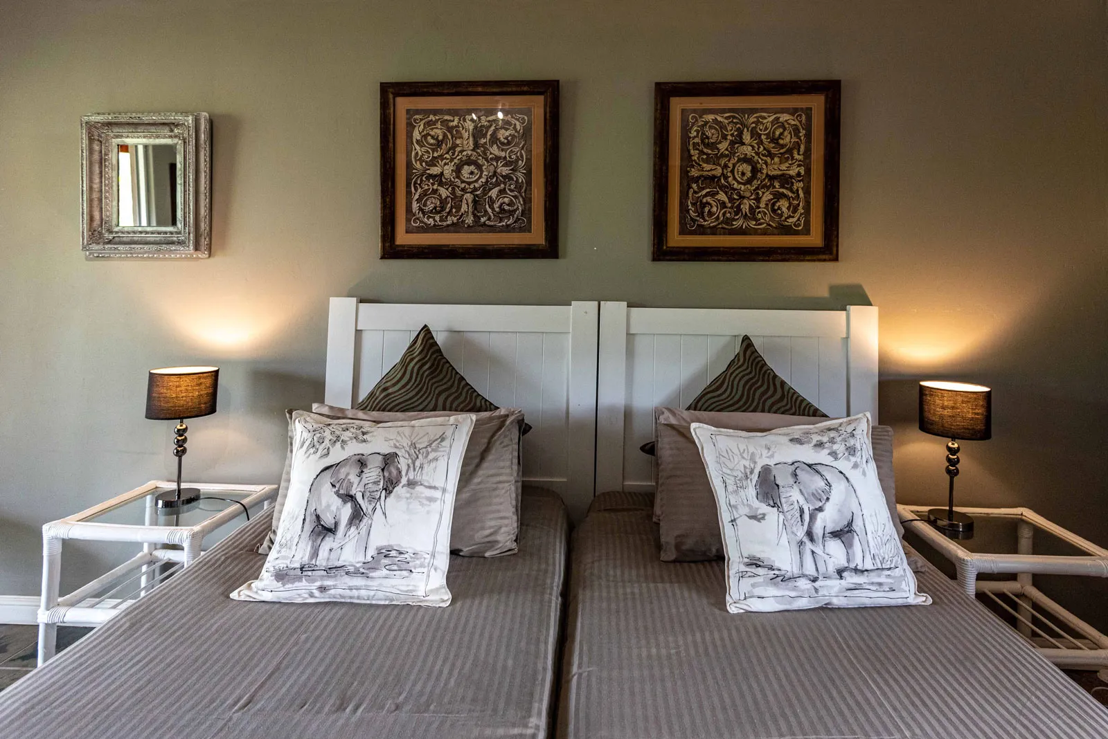 Twin beds with elephant pillows framed art and bedside lamps in a bedroom