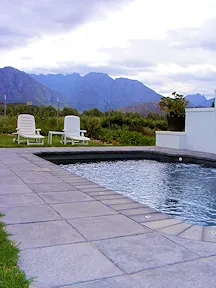 Swimming pool with lounge chairs garden and mountains in the background