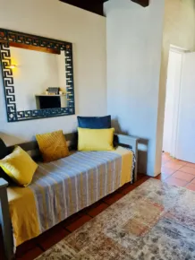 Daybed with yellow and blue pillows in a cozy room with tiled floor