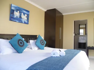 Bedroom with a neatly made bed blue pillows and a wardrobe