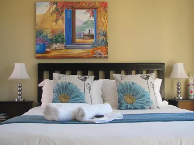 Bed with blue floral pillows white towels and a colorful painting above