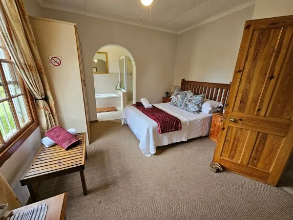 Cozy bedroom with a large bed wooden door and an ensuite bathroom