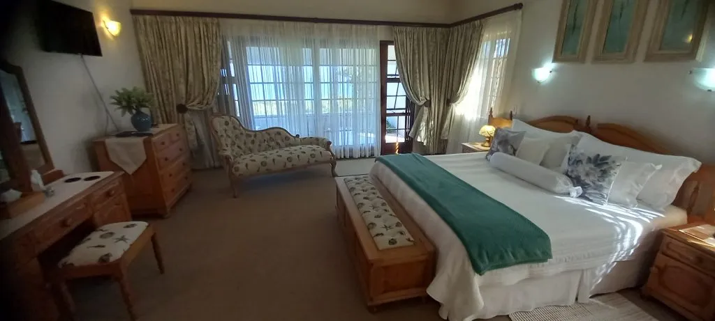 Cozy bedroom with large bed armchair and large windows with curtains