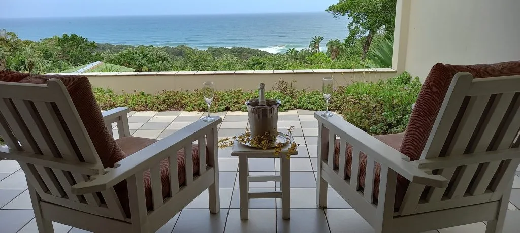 Two chairs facing ocean view with a table and wine glasses