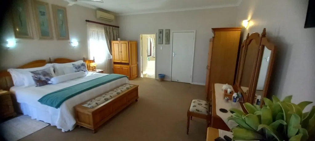 Cozy bedroom with large bed wooden furniture and a potted plant