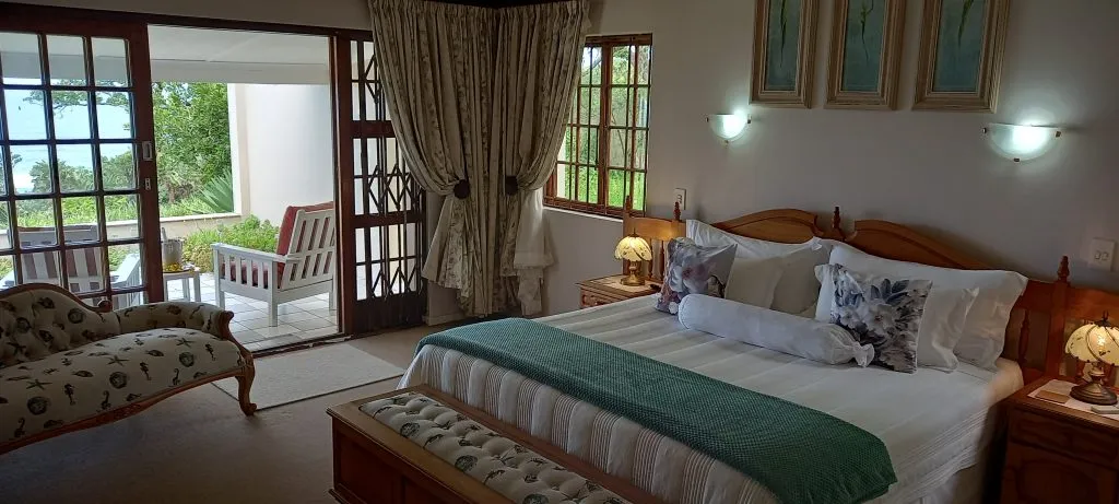 Cozy bedroom with large bed green throw and outdoor patio view