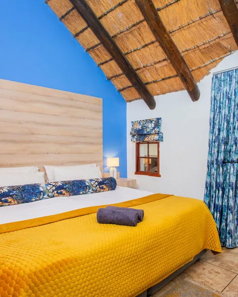 Bedroom with yellow bedding blue walls and a thatched ceiling
