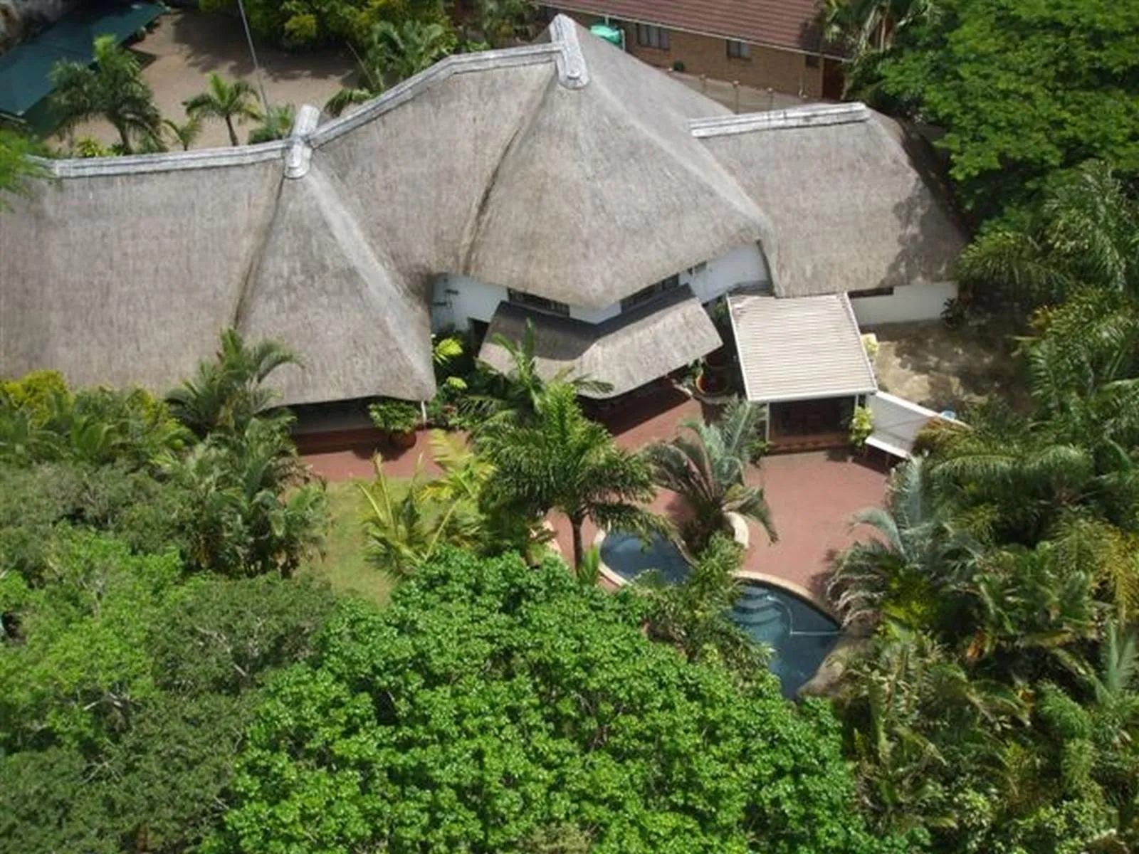 Aerial view of a house with a pool surrounded by lush greenery