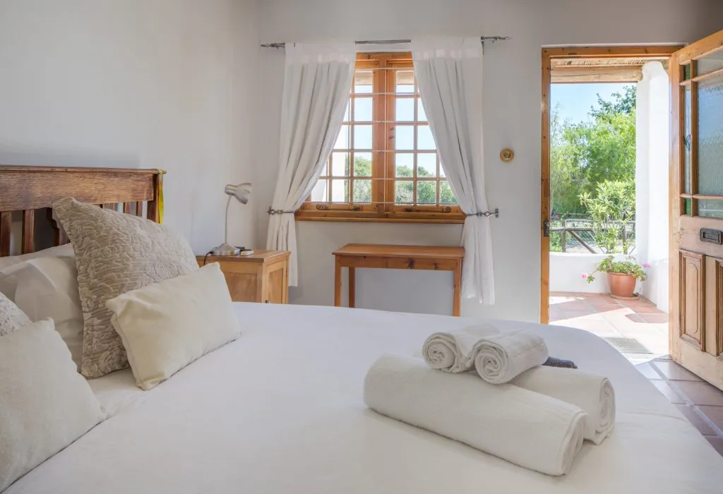 Bright bedroom with open door to patio white towels on bed and pillows