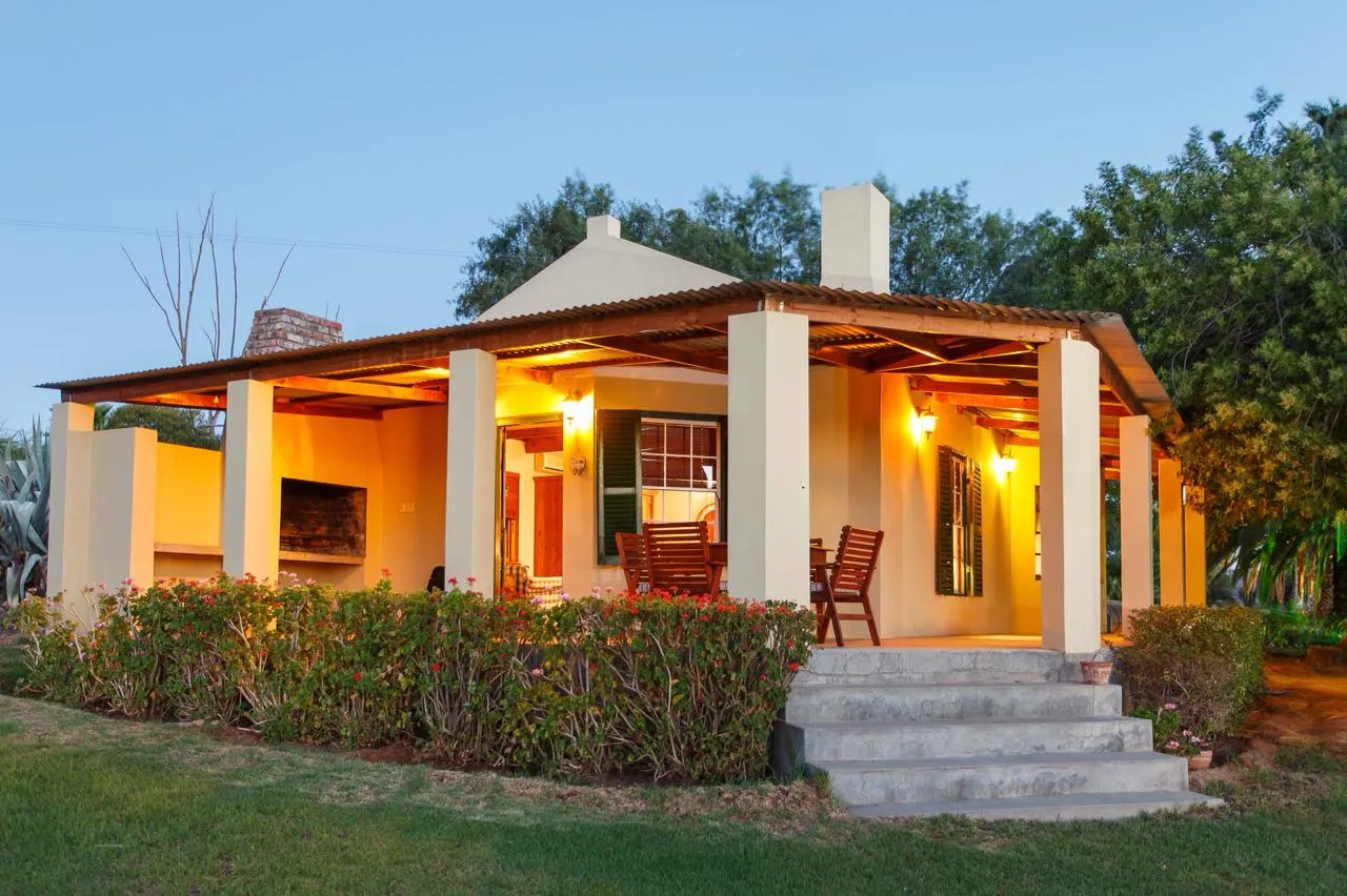 Cozy house with porch and outdoor seating surrounded by greenery at dusk