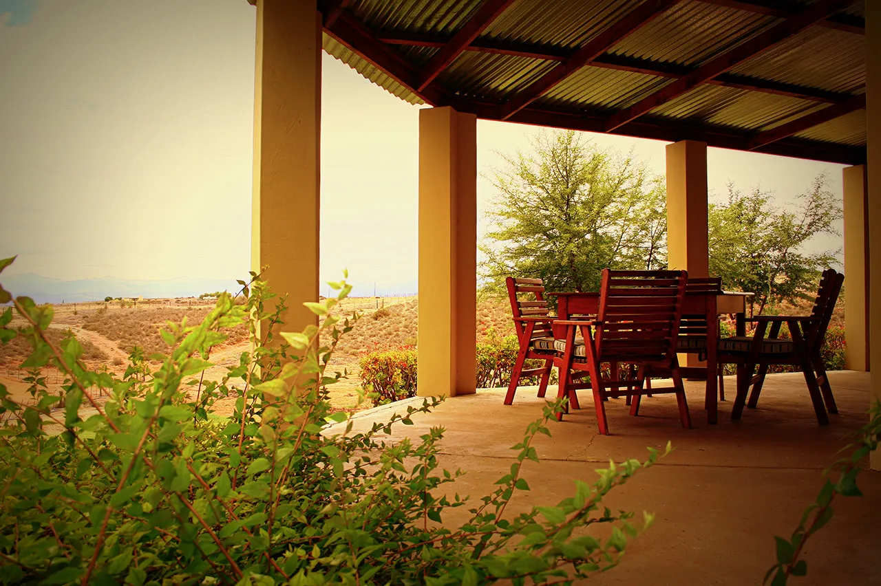 Wooden chairs and table on a patio with desert landscape in the background