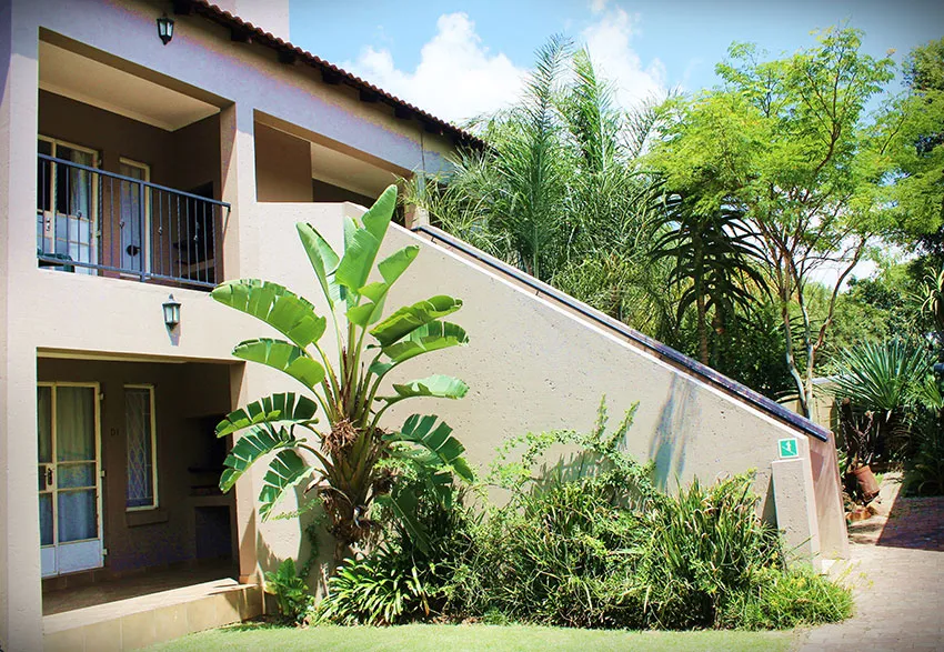 Modern building with balconies lush greenery and a sloped pathway in a garden