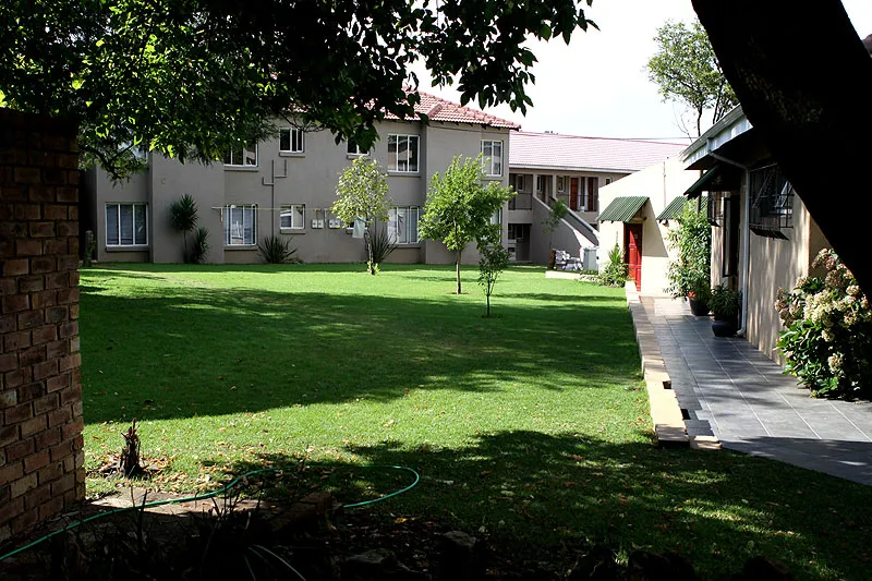 Courtyard with green lawn trees and apartment buildings in the background