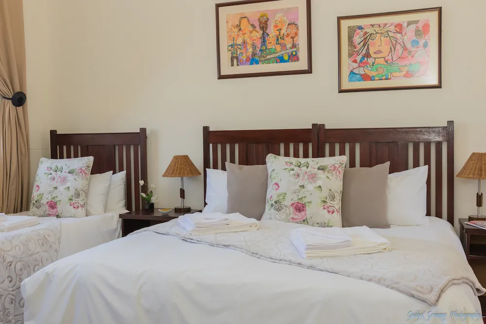 Two beds with floral pillows wooden headboards and framed artwork above them