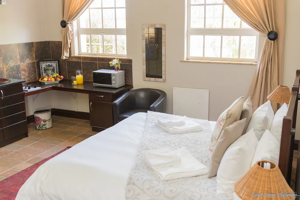 Cozy bedroom with a bed desk microwave and large windows with curtains