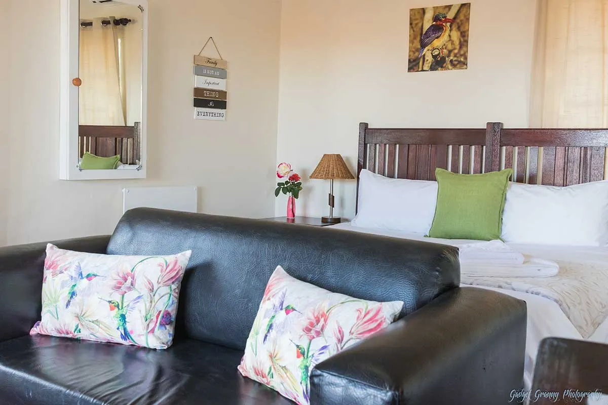 Bedroom with a black sofa floral pillows bed and wall art