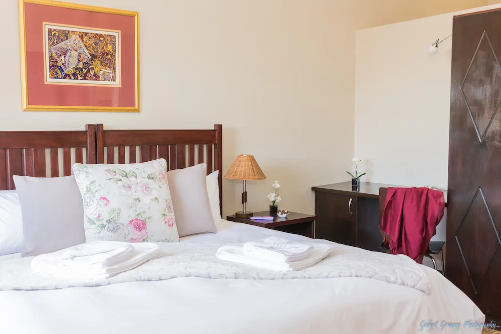 Cozy bedroom with a neatly made bed nightstand and wall art
