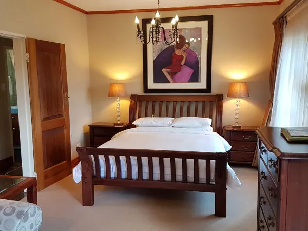 Wooden bed with white bedding in a cozy bedroom with a large wall painting