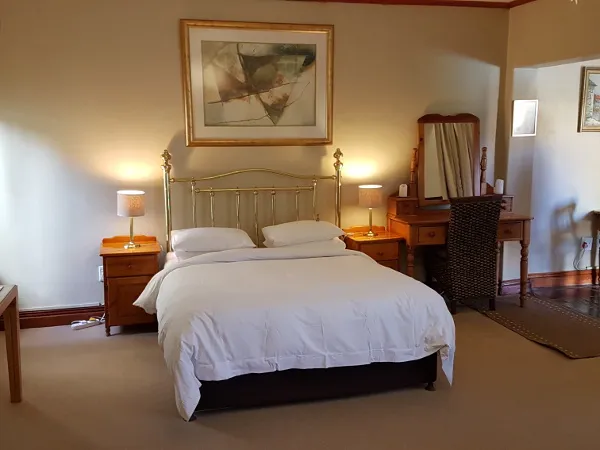 A neatly made bed in a welllit bedroom with wooden furniture