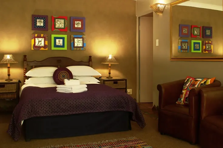 Cozy bedroom with a large bed colorful framed pictures and a brown armchair