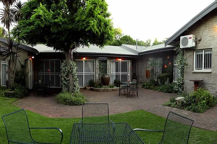 Courtyard with brick patio trees and outdoor seating near a house