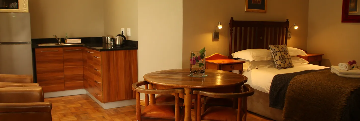 Cozy hotel room with a bed wooden table chairs and kitchenette