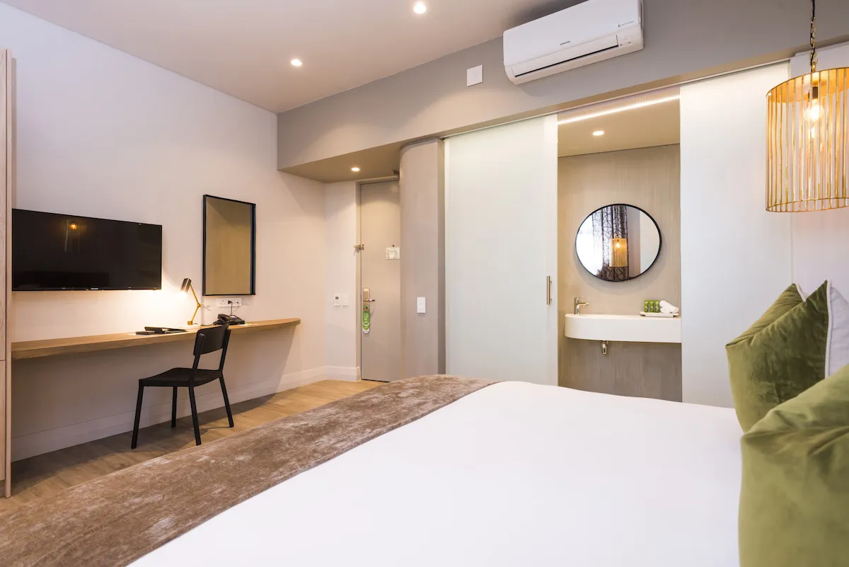 Modern hotel room with bed desk TV and open bathroom area