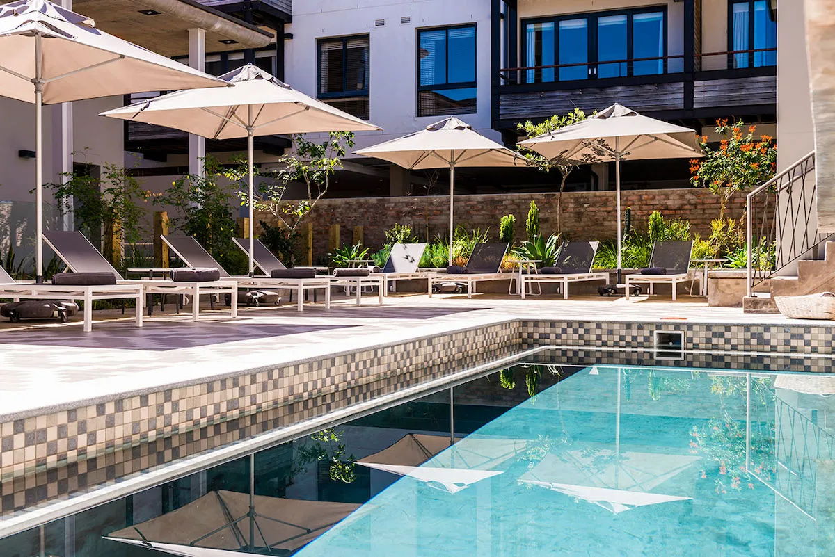 Swimming pool with lounge chairs and umbrellas by a building