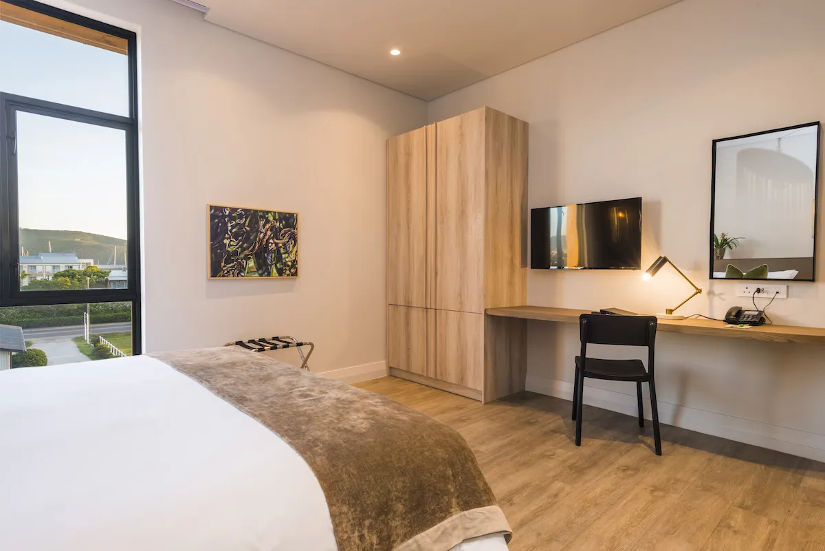 Modern hotel room with bed desk TV and large window view