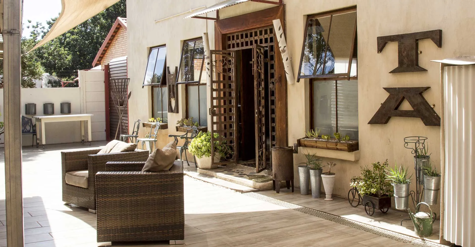 Outdoor seating area with wicker chairs and potted plants near a building entrance