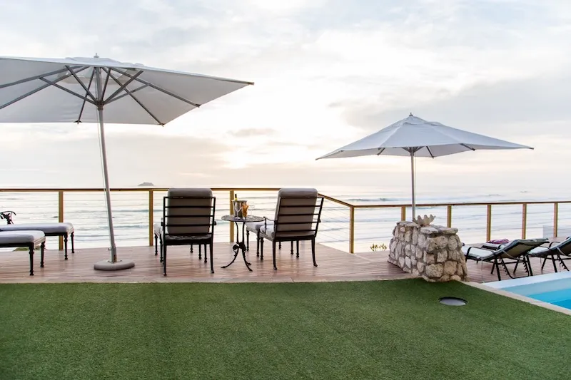 Two lounge chairs with umbrellas on a wooden deck overlooking the ocean