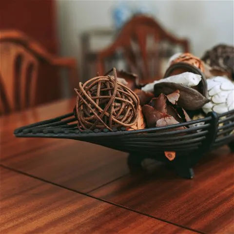 Decorative bowl with dried leaves and balls on a wooden table