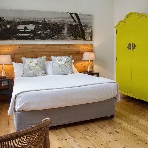 Bright bedroom with wooden floor white bed and yellow wardrobe