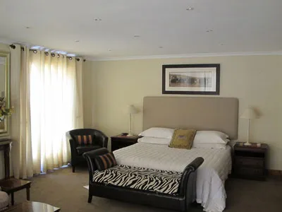 Bedroom with large bed striped bench and two bedside tables with lamps