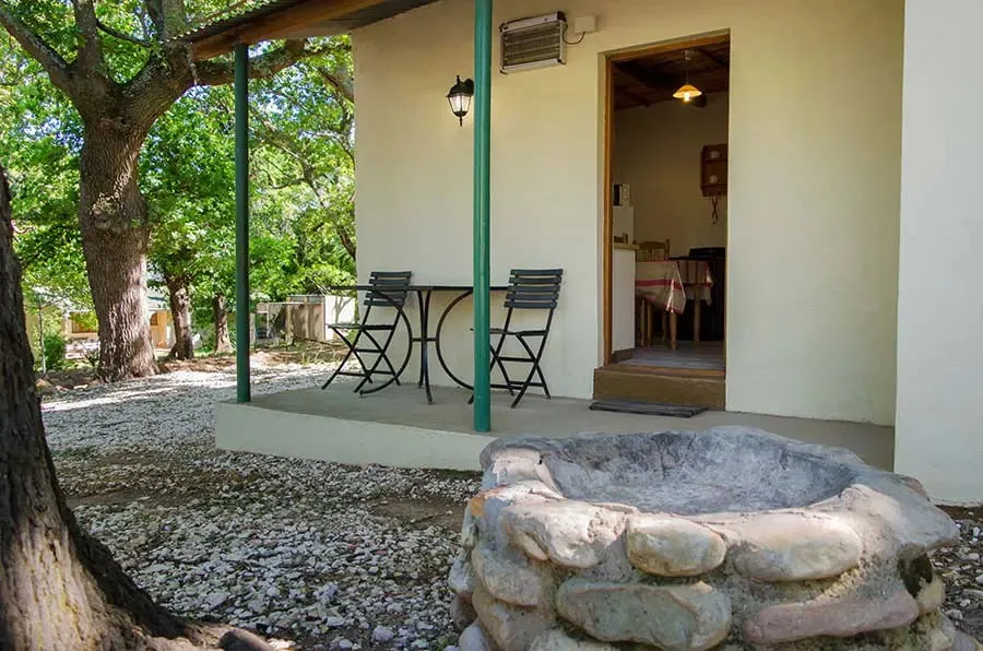 Cottage entrance with outdoor seating and stone well surrounded by trees