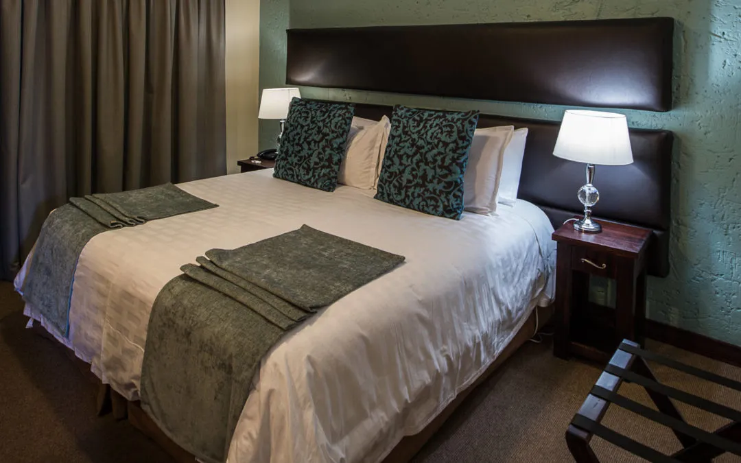 A neatly made bed with pillows and bedside tables in a bedroom