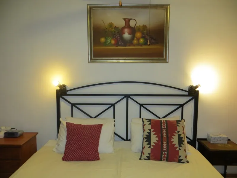 Bedroom with a bed two pillows and a painting above the headboard