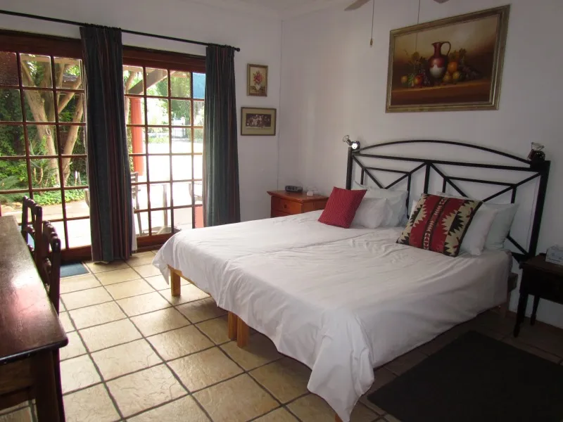 Bedroom with two single beds painting and large window with blue curtains