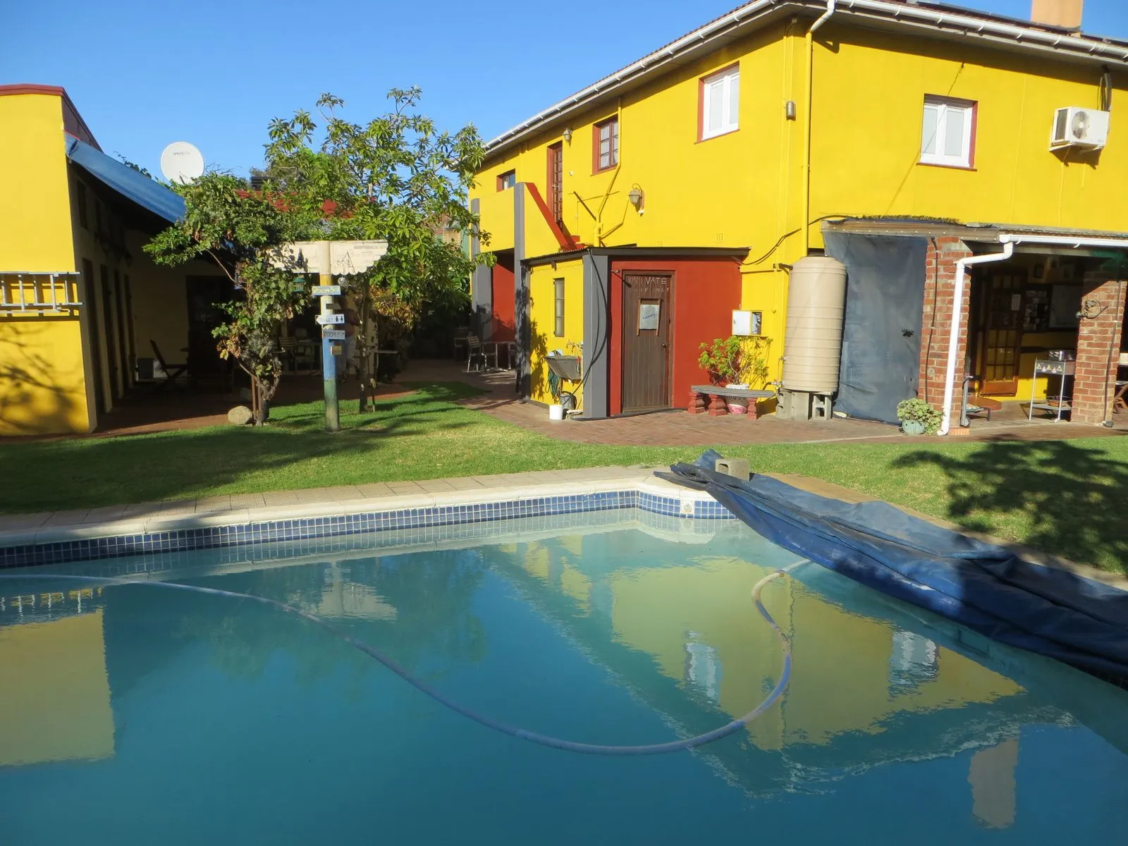 A yellow house with a swimming pool in the garden
