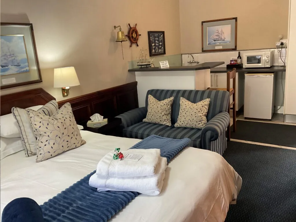 Cozy bedroom with a bed sofa and kitchenette in the background