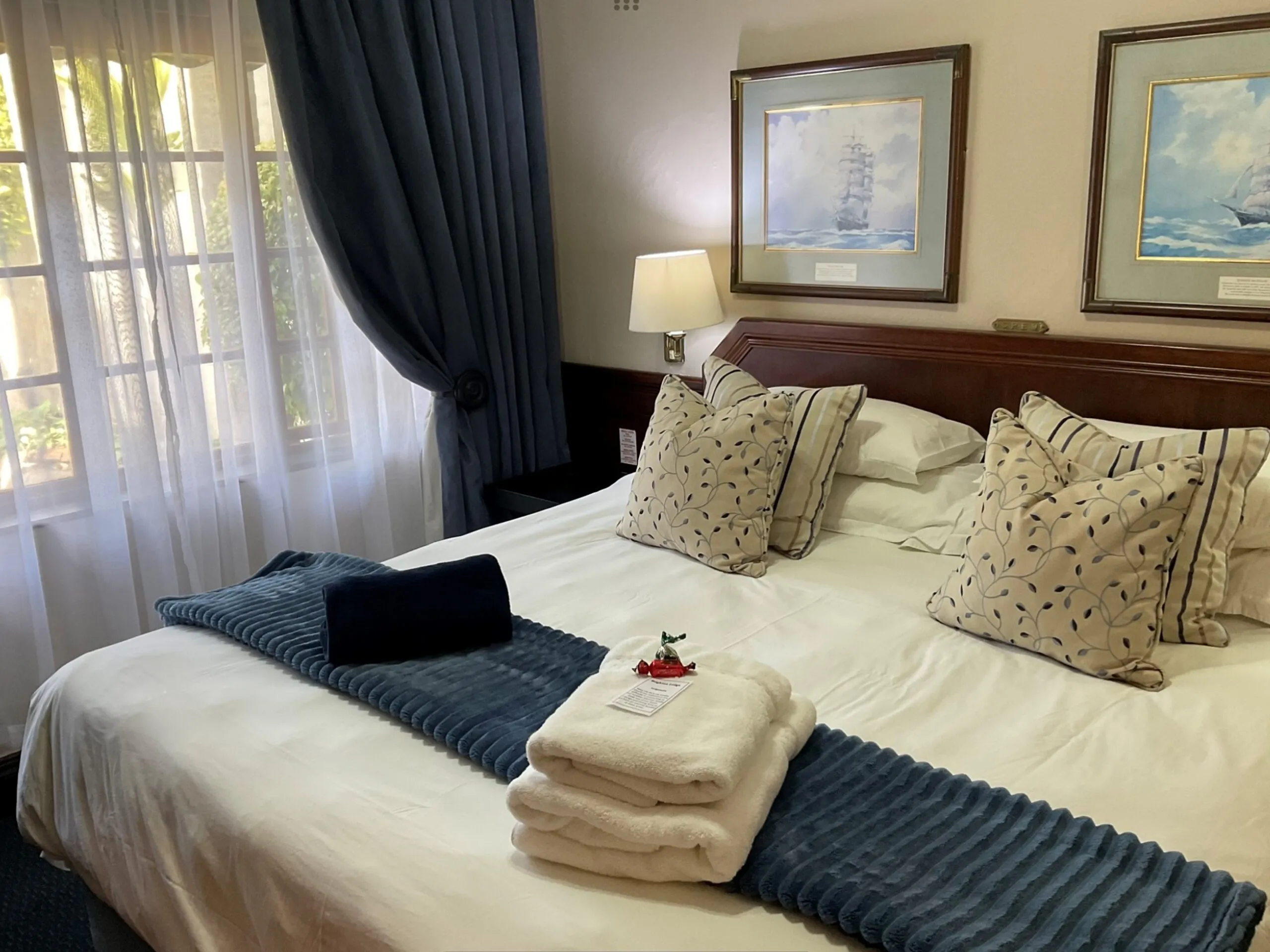 A neatly made bed with pillows folded towels and a bedside lamp