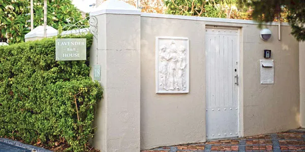 White door with sign Lavender Tea House on beige wall with greenery